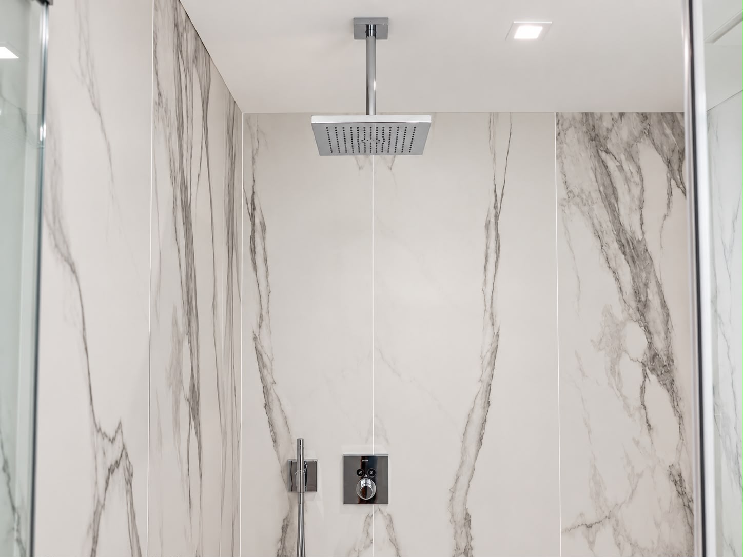 Frameless glass rain shower in marble